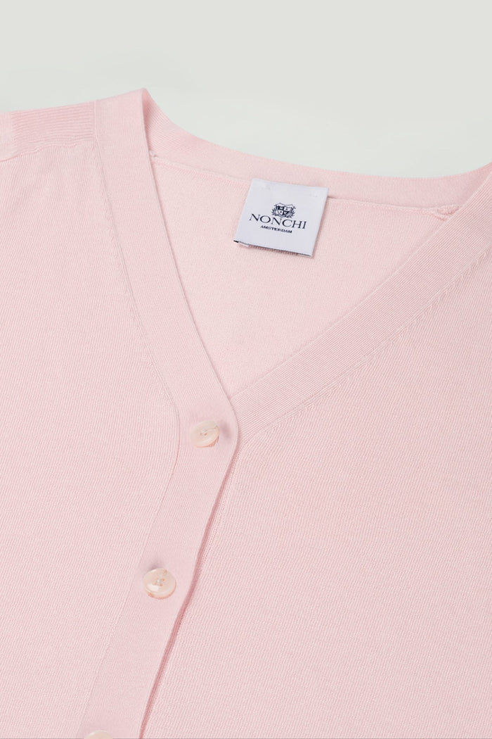 Pink cardigan with a brand label on a light gray background. | Exclude
