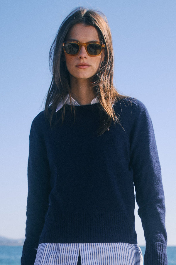 Woman wearing sunglasses and a dark sweater with a clear blue sky background | Grid Hover | Exclude