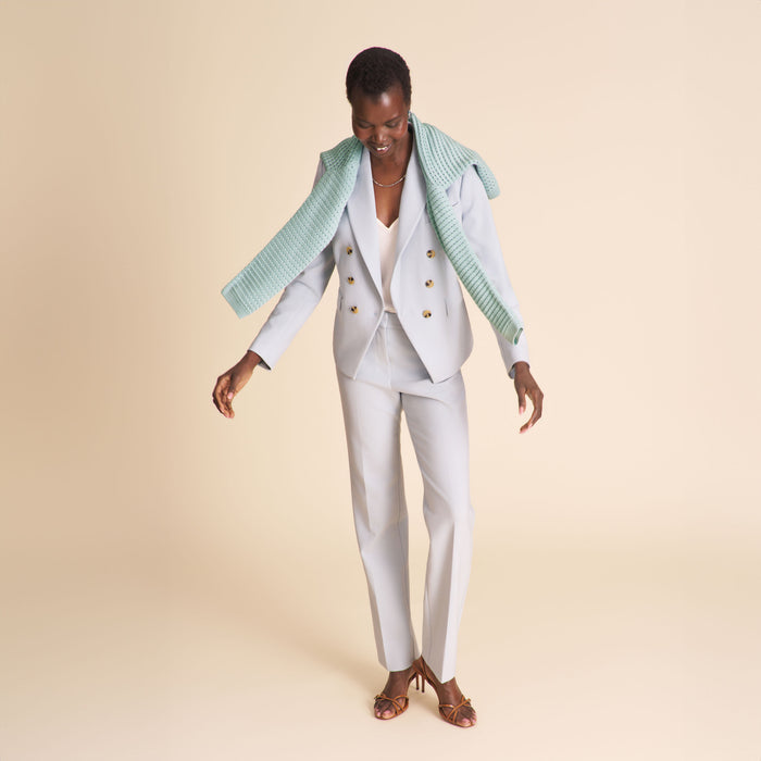 Woman wearing a light blue blazer and matching pants on a beige background