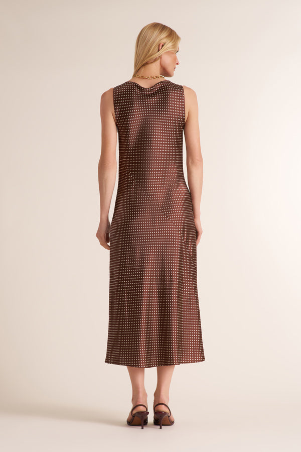 Woman wearing a sleevless maxi dress in a brown and white dot print | Exclude