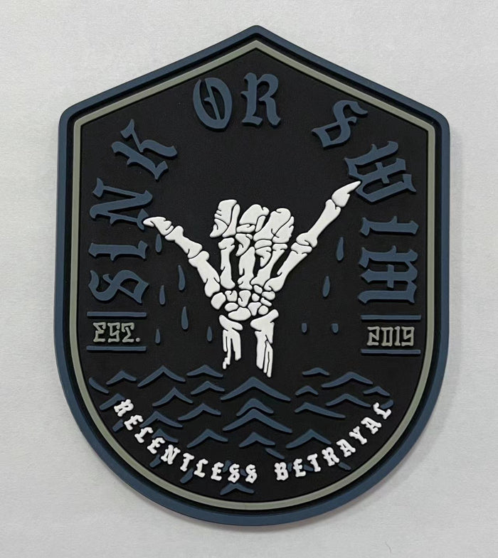 The Sink or Swim PVC Patch by Relentless Betrayal displays a skeleton hand making the rock and roll gesture. Sink or Swim is highlighted above, with Relentless Betrayal below flanked by Est. 2019. Water waves beneath the hand suggest flotation in a pool setting.