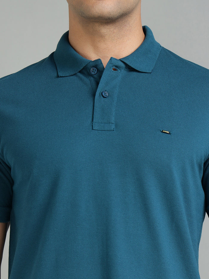 Teal polo shirt with a small logo on a gray background
