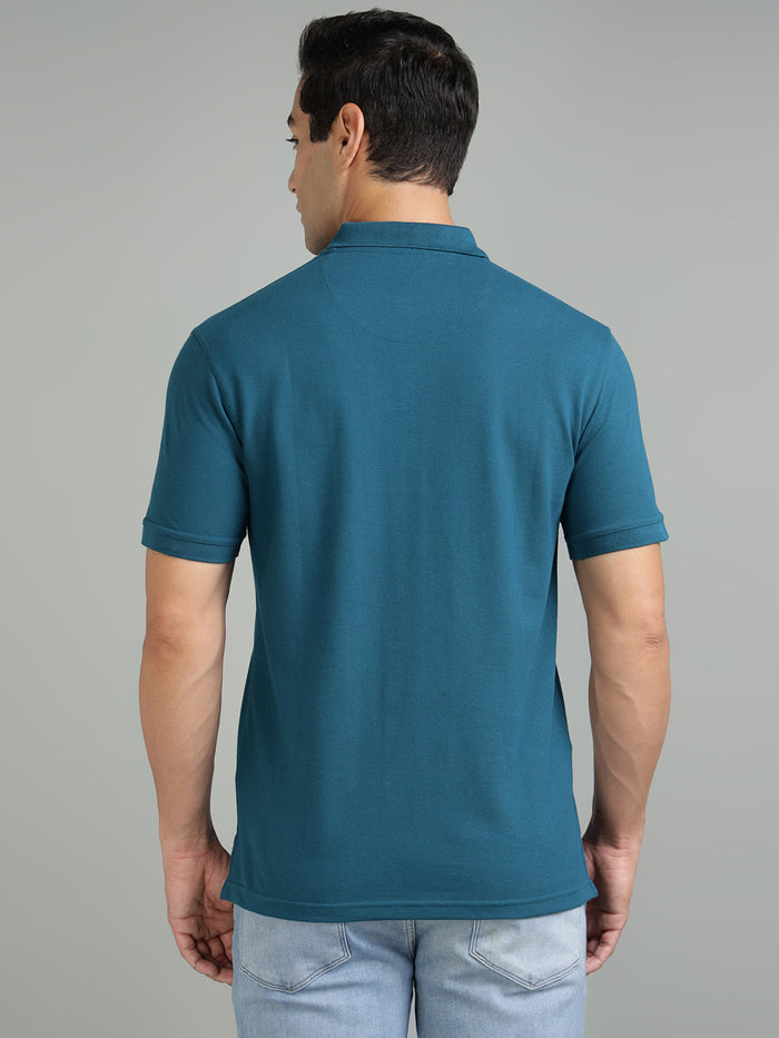 Man wearing a teal polo shirt against a gray background