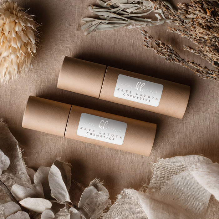Custom personalized white glossy rectangular business branding stickers with curly monograms and serif info text in silver foil print placed on kraft cosmetic tubes - XOXOKristen