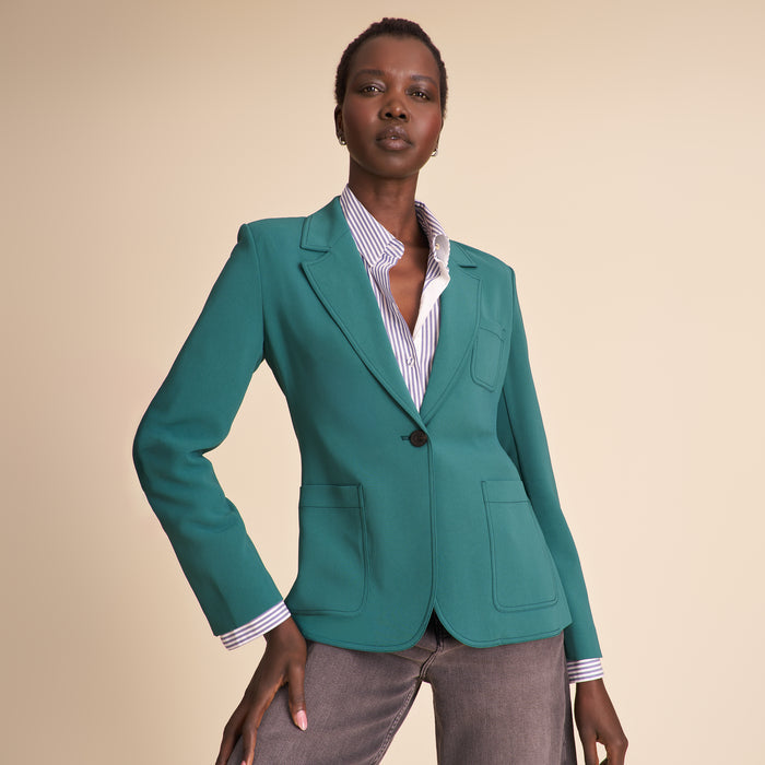 Woman wearing a teal suit against a beige background