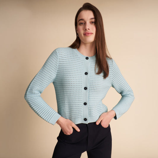 Woman wearing the Zosia cardigan in light blue on a beige background | Lead
